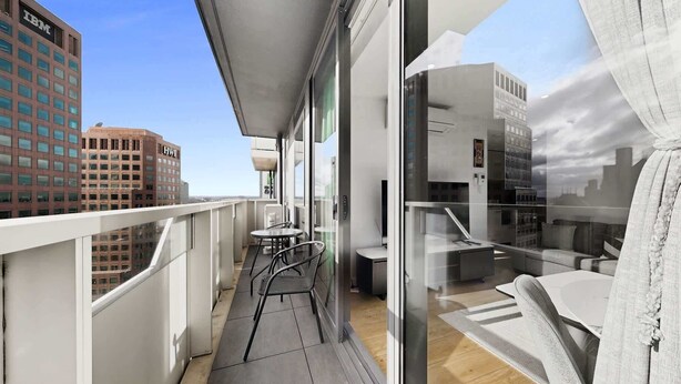 Een balkon met een tafel en stoelen, uitzicht op de stad en een blik in het interieur.