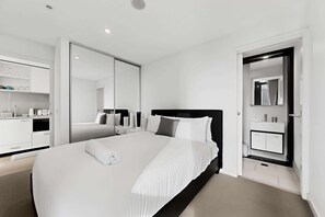 Ein modernes Hotelzimmer mit einem großen Bett, einem separaten Badezimmer und einer Küchenzeile.