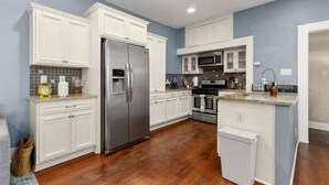 Uma cozinha moderna com armários brancos, eletrodomésticos de aço inoxidável e painel de azulejos.