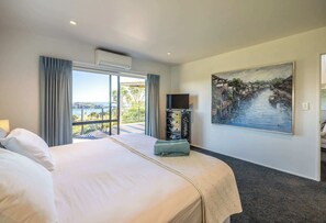 Habitación de hotel con una cama grande, televisión, un cuadro y vista a un cuerpo de agua.