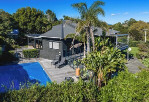 Una casa moderna con piscina, terraza y zona de estar exterior cubierta.