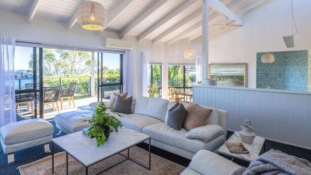 Uma sala de estar moderna com sofá, mesa de centro e vista para o exterior.
