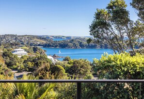 A coastal landscape with a clear view of a bay, a sailboat, and residential buildings.