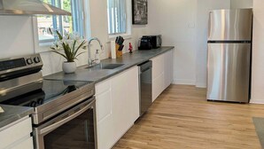 Een moderne keuken met roestvrijstalen apparatuur, witte kastjes en een houten vloer.