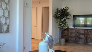 Een woonkamer met een ronde tafel, een potplant en een televisie.