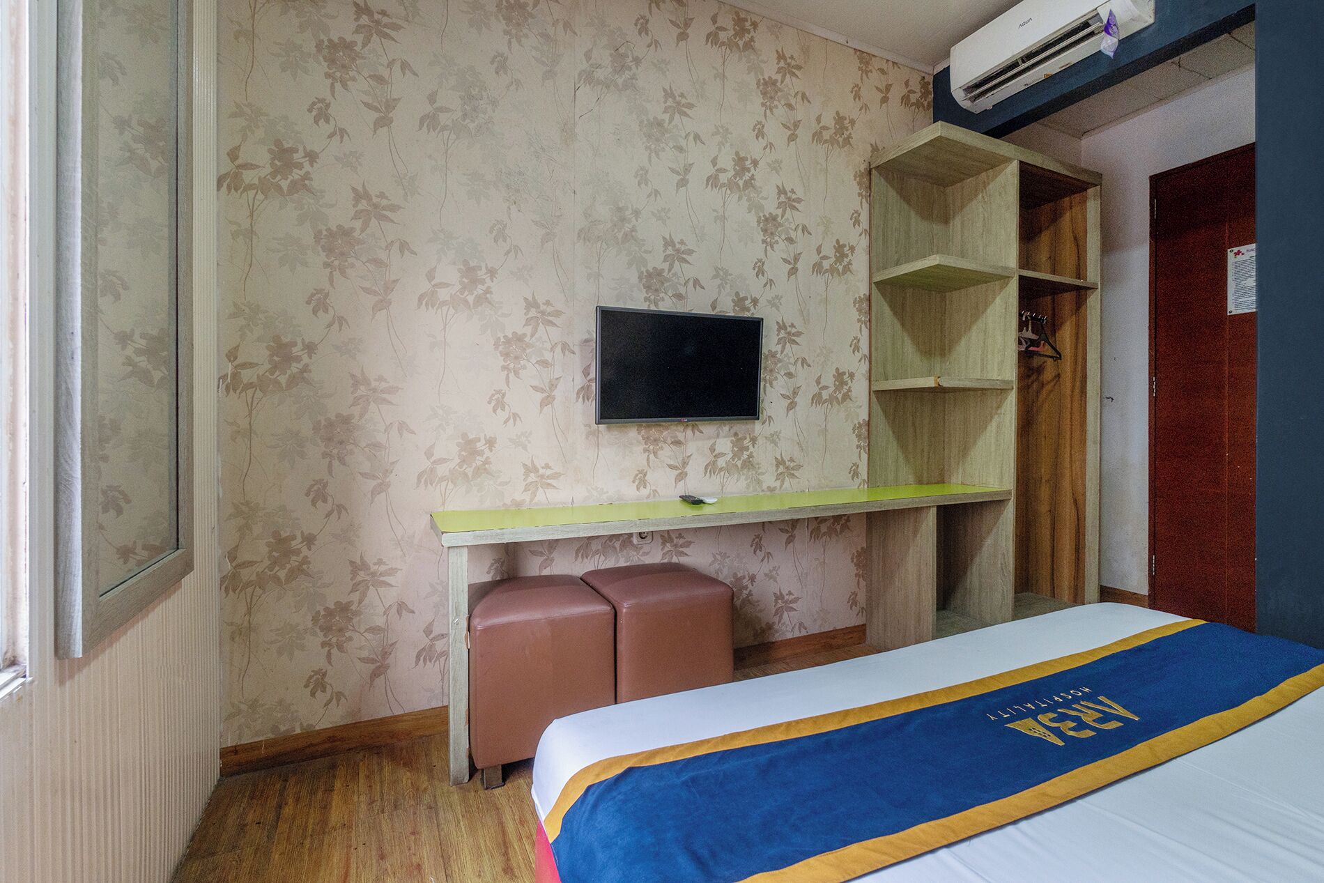 A room with a bed, a desk, a chair, a television, and a wardrobe.