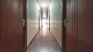 Een lange, smalle gang met deuren aan beide kanten, die naar kamers leidt.