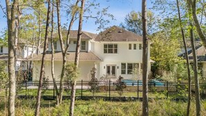 Una casa de dos pisos con jardín delantero y piscina.