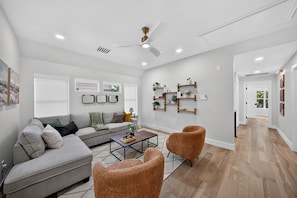 A modern living room with a grey sofa, two armchairs, a coffee table, and built-in shelves with decorative items. - The Woodlands Luxe 5BR/4.5BA Heated Pool and Grill (Spring)