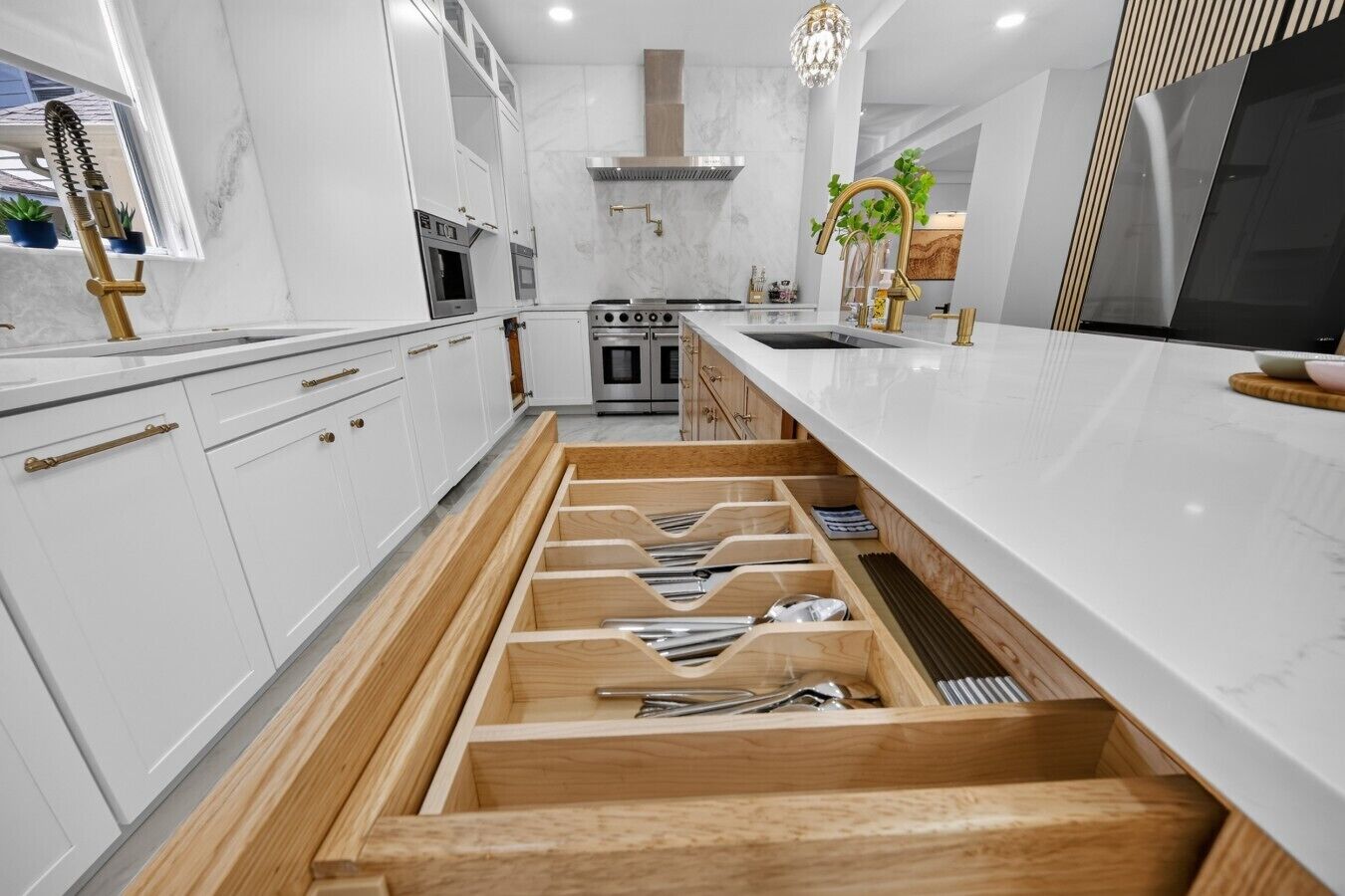 Une cuisine moderne avec des meubles blancs, un four encastré et un meuble à tiroirs en bois.