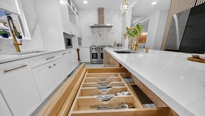 Una cocina moderna con armarios blancos, horno integrado y una unidad de cajones de madera.