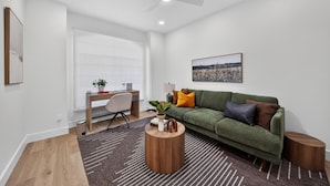 Una sala moderna con un sofá verde, una mesa de centro de madera y un escritorio con una silla.
