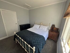 A bedroom with a bed, a nightstand, a dresser, and a door.