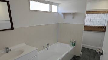 Un bagno con una vasca, due lavandini, uno specchio e una finestra.
