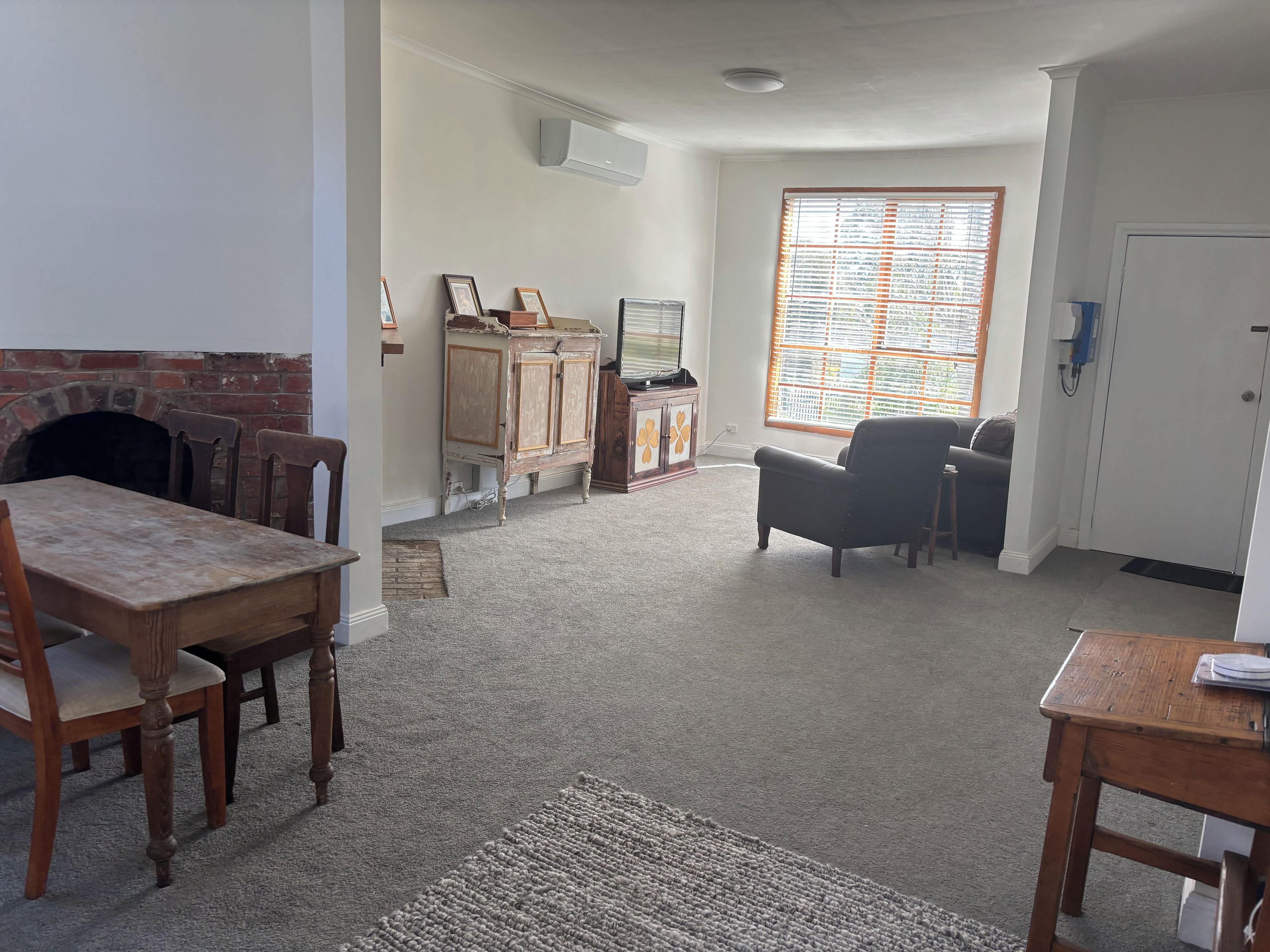 A living room with a fireplace, a television, a sofa, and a dining area with a table and chairs.