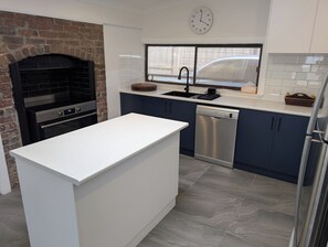 A modern kitchen with a brick fireplace, stainless steel appliances, and a dishwasher.