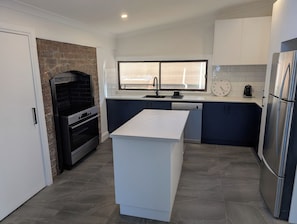 A modern kitchen with a central island, built-in oven, and stainless steel appliances. - Charming Home in Ballarat near Sovereign Hill (Mount Pleasant)