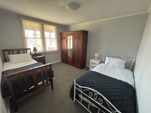 Een slaapkamer met twee bedden, een garderobe en een nachtkastje met een lamp.