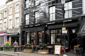 A building with a black facade and a mural, featuring a restaurant named 'A Mexican Joint' with outdoor seating. - Chic Four-Bedroom Townhouse in cool Notting Hill (Greater London)