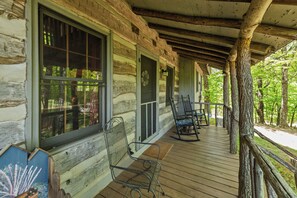 Eine Holzhütte mit einer Holzdachterrasse, Metallstühlen und einer Veranda.
