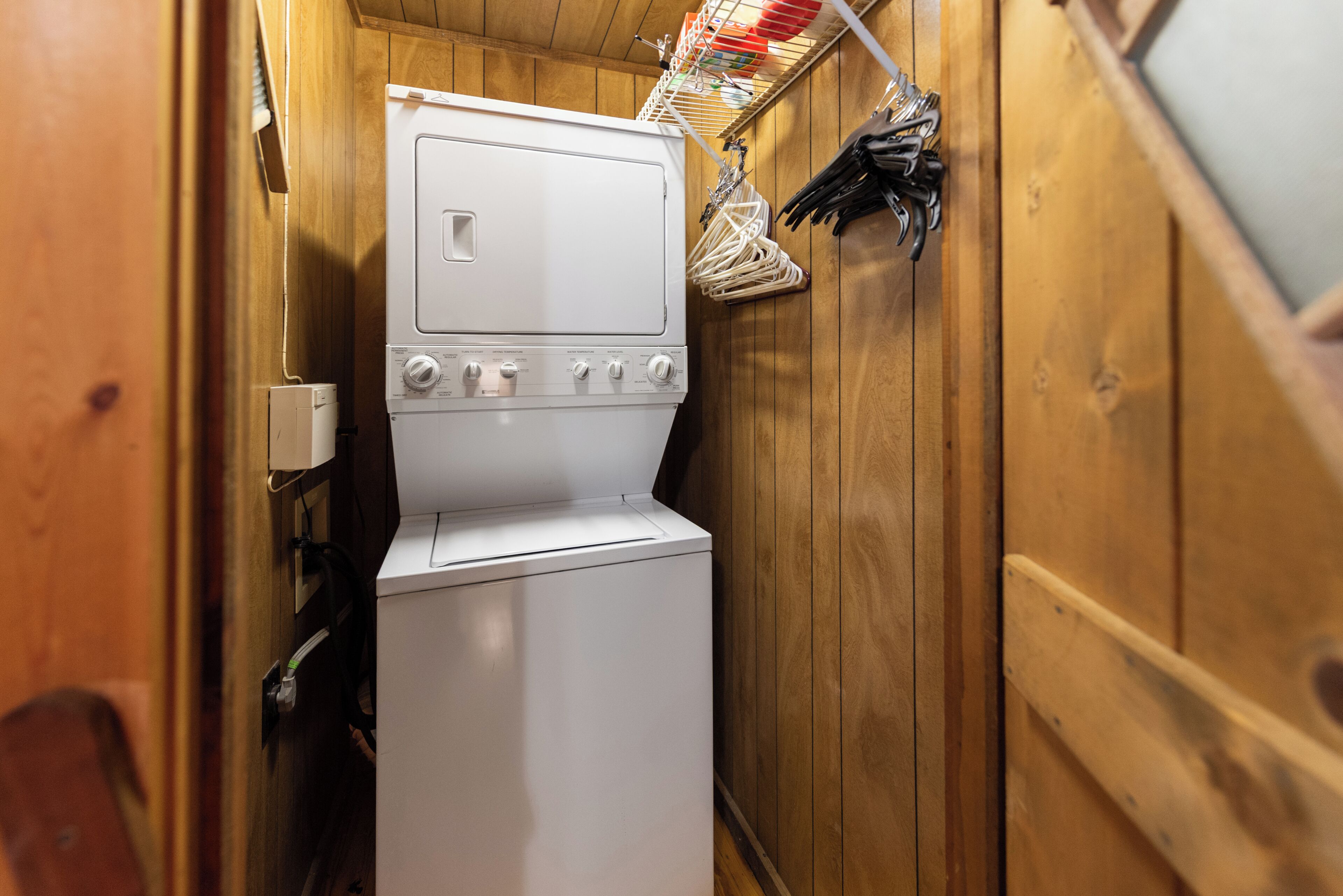 Un espace buanderie compact comprenant un lave-linge et un sèche-linge, des murs en bois et un étendoir pour suspendre le linge.