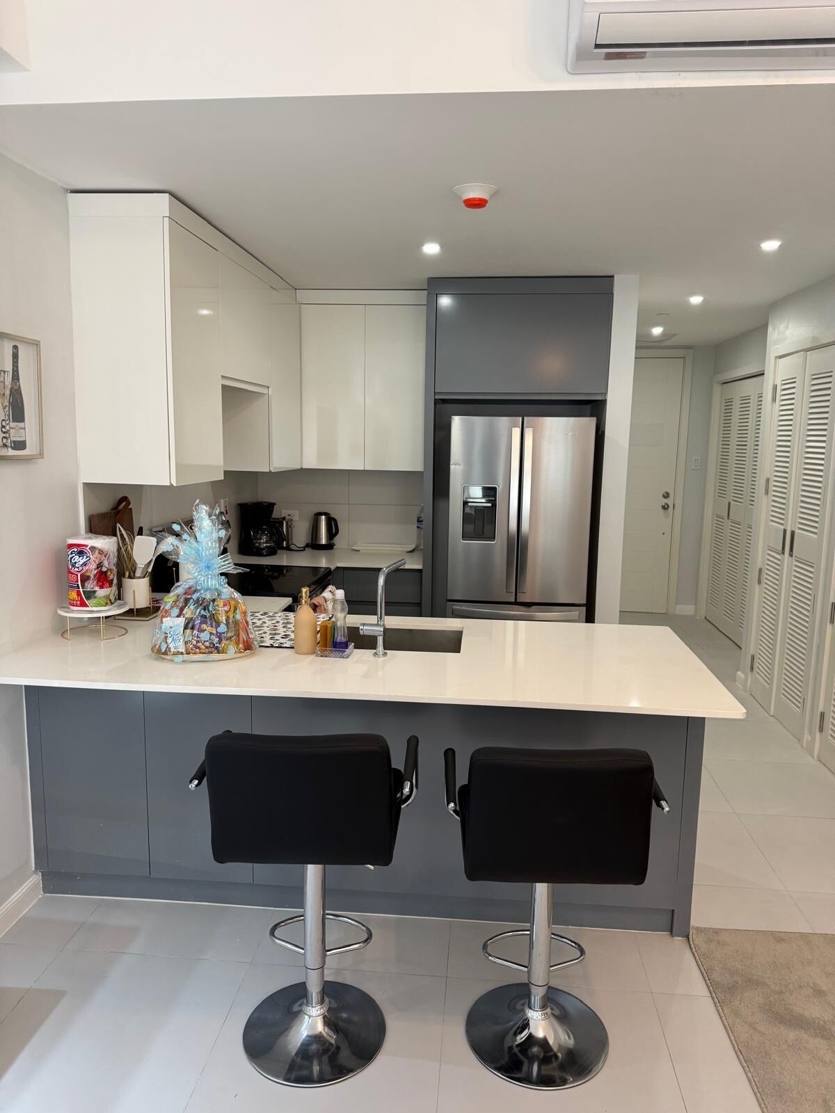 A modern kitchen with a central island, stainless steel appliances, and black bar stools.