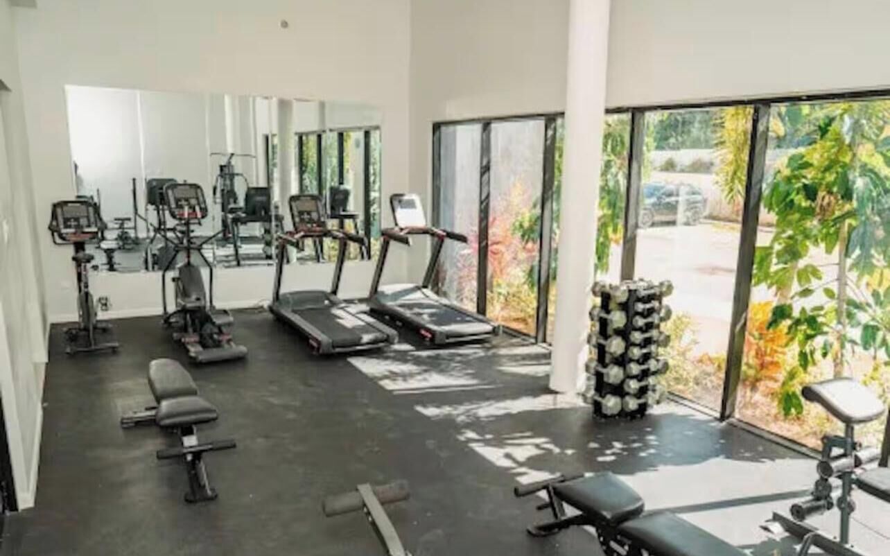 A gym with exercise equipment, large windows, and a view of the outdoors.