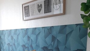 A dining area with a geometric patterned wall, a framed quote, and a vase with yellow flowers on a table. - Azul Puerto Del Malecon (Puerto Plata)