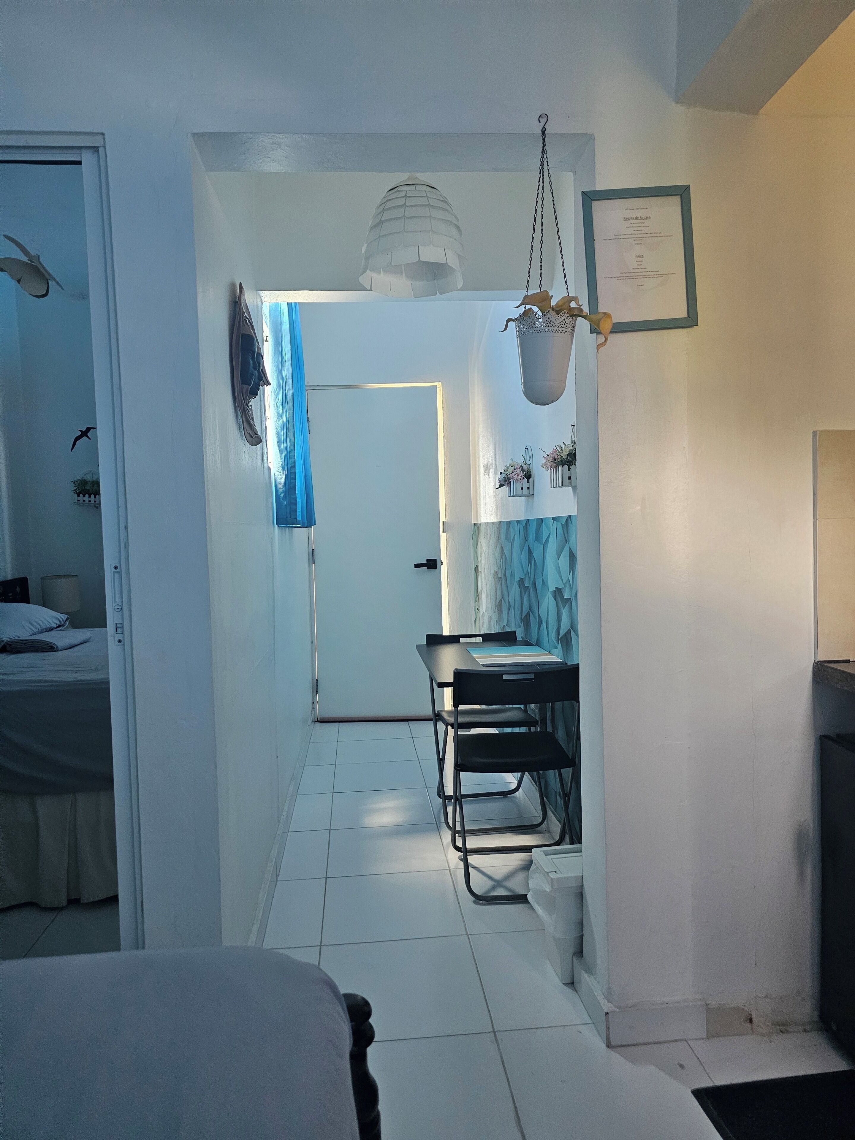 Une chambre d’hôtel avec un lit, un bureau et des chaises, un luminaire suspendu et un certificat encadré accroché au mur.