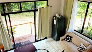 Habitación moderna con sofá, una mesa, sillas, una lámpara colgante y vistas amplias a través de grandes ventanales.