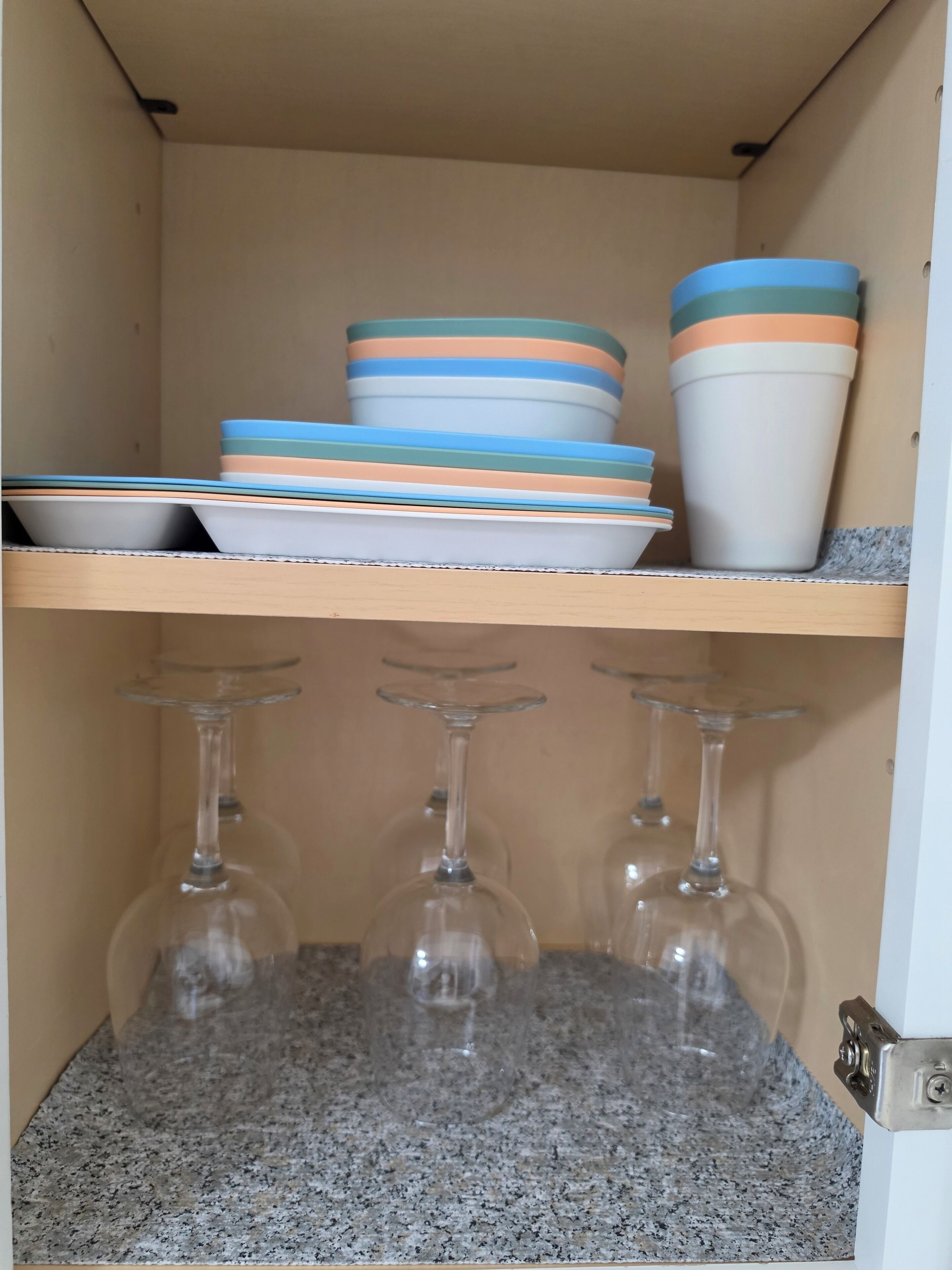 Un meuble de cuisine avec une pile d’assiettes et un verre à vin en verre.