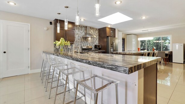 A modern kitchen with a marble island, bar stools, stainless steel appliances, and pendant lighting. - Perfect Group Getaway w/ Private Pool (Las Vegas)