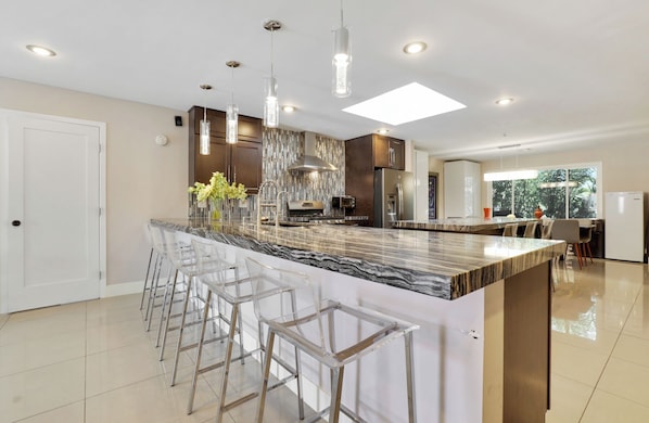 A modern kitchen with a marble island, bar stools, stainless steel appliances, and pendant lighting. - Perfect Group Getaway w/ Private Pool (Las Vegas)