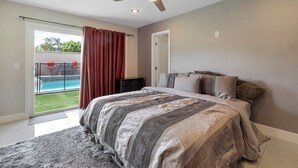 A bedroom with a bed, a ceiling fan, a view of a swimming pool, and a door to the outside. - Perfect Group Getaway w/ Private Pool (Las Vegas)