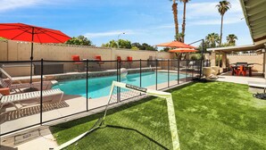 A backyard with a swimming pool, a covered patio, and a fenced area with lounge chairs. - Perfect Group Getaway w/ Private Pool (Las Vegas)