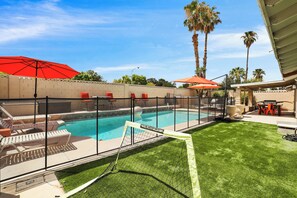 A backyard with a swimming pool, a covered patio, and a fenced area with lounge chairs. - Perfect Group Getaway w/ Private Pool (Las Vegas)