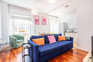 Una sala moderna con un sofá azul, un sillón verde y una mesita auxiliar.