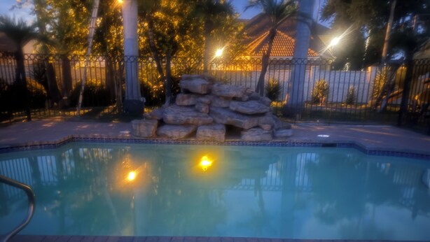 A swimming pool with a stone feature, surrounded by a brick patio and a fence. - Charming apartment in awesome Mission with cool AC breeze (Mission)
