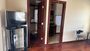 A room with a TV on a stand, a chair, and a wooden floor. - Charming apartment in awesome Mission with cool AC breeze (Mission)