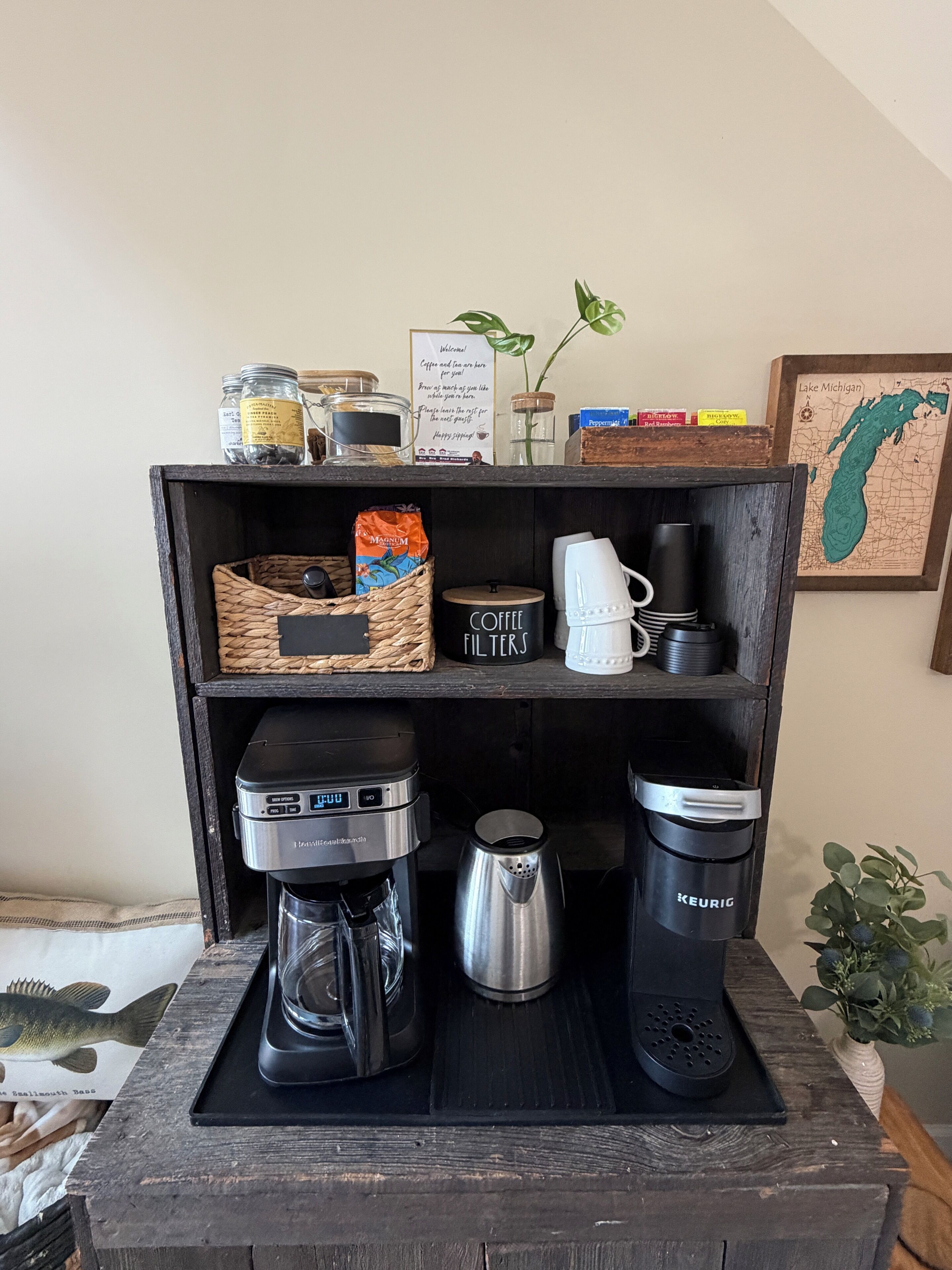 A coffee station with a coffee maker, a kettle, and a mug on a wooden shelf.