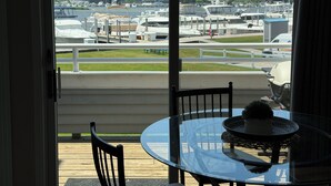 Blick von einem Balkon mit Glastisch und Stühlen auf einen Yachthafen mit Booten und einem Schild mit der Aufschrift 'Grand Isle Marina'.