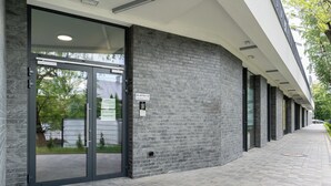 Un bâtiment avec une entrée en verre, une enseigne indiquant « KLATKA B », et un trottoir dallé.