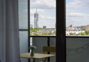 Una habitación con vista a un paisaje urbano, que incluye un edificio alto, a través de una ventana.
