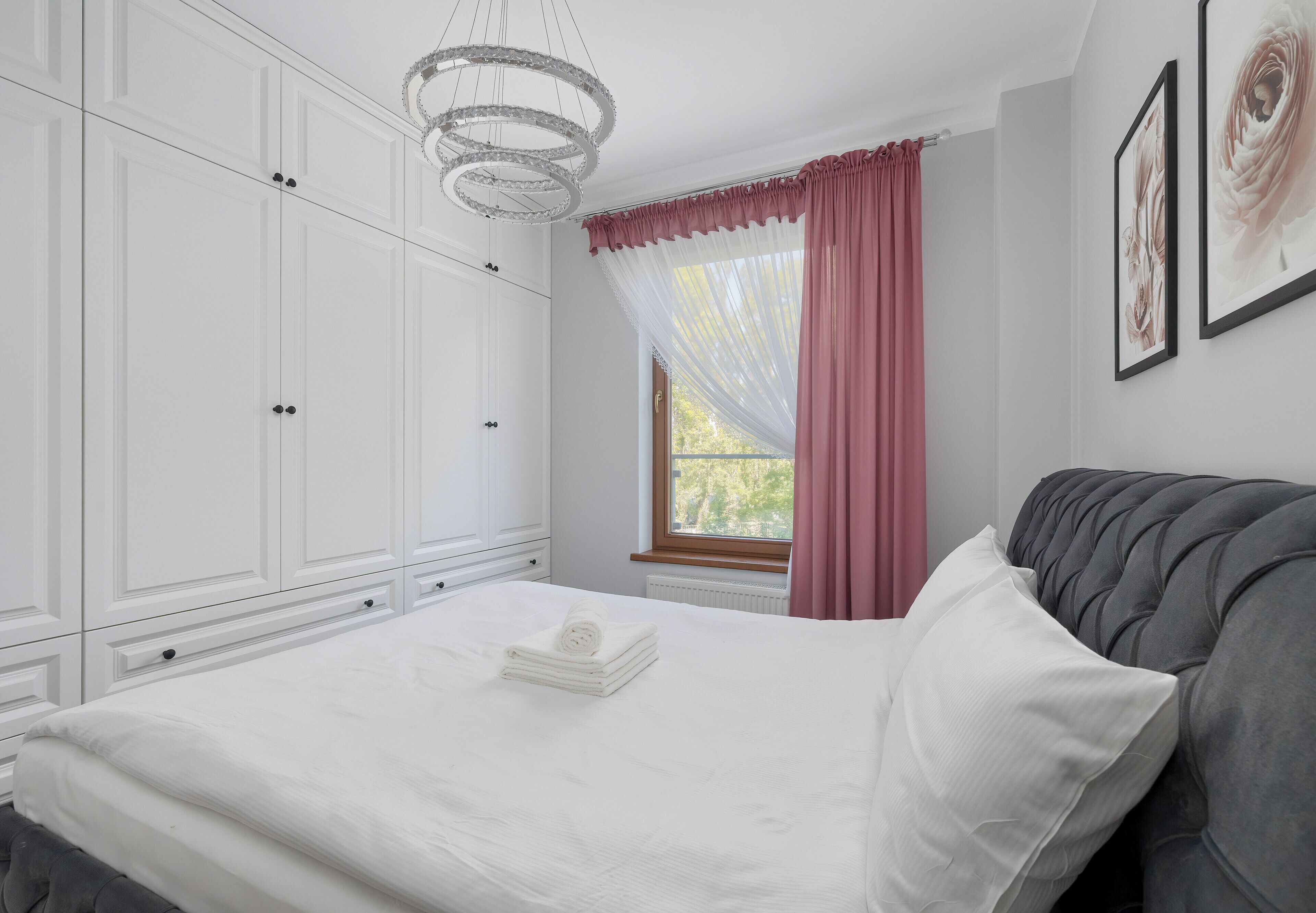 Une chambre à coucher avec un lit, une armoire blanche et une fenêtre avec des rideaux.