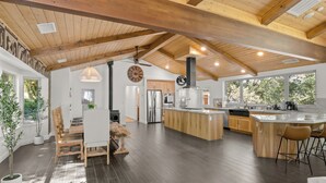 A spacious kitchen with a central island, wooden beams on the ceiling, and large windows.