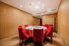 A conference room with a round table, red chairs, and a podium.