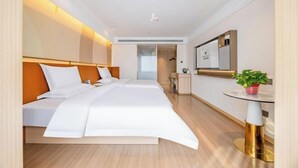 Una habitación de hotel con cama, mesita de noche y una pequeña planta en maceta.