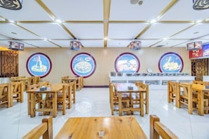 A restaurant with wooden tables and chairs, a counter with a menu, and wall decorations.
