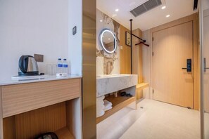 A modern bathroom with a wooden vanity, a mirror with a light, and a shower area.