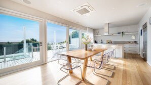 A modern kitchen with a dining area, large windows, and a view of the outdoors.